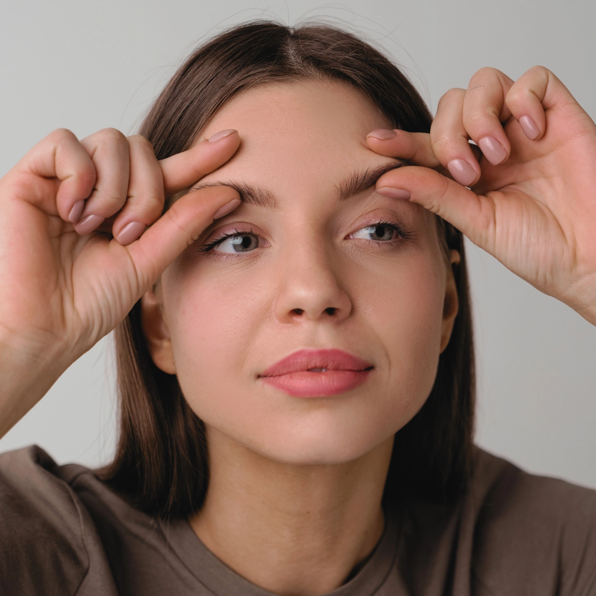 Naine teeb näojooga harjutust, tõstes kulme kahe sõrmega ülespoole.
